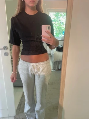 Svart topp med knyt - Säljer en svart croppad topp med korta ärmar och snygg knytning i ryggen. Säljer även en rosa likadan också. Toppen har en tight passform och är perfekt för dig som vill ha en trendig och stilren look. Passar till både jeans och kjol.