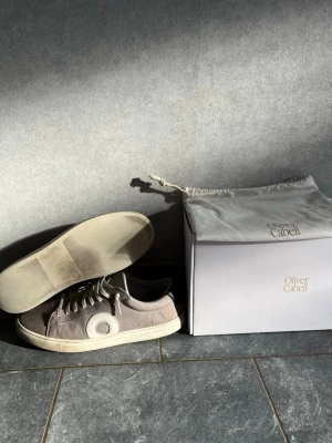 Gråa Oliver Cabell sneakers - Snygga gråa sneakers från Oliver Cabell i Italienskt slitet läder, nubuck, gråa premium bomullssnören och en slitstark, dämpad sula. Perfekta för dig som gillar skor som har en sliten och clean stil. Skorna är i storlek 43. Allt som är med på bilden ingår. Nypris runt 3700kr med tull och frakt och mitt pris 1300kr.. Kan gå ner lite i pris vid snabb affär🤝