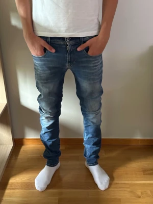 Replay jeans  - Säljer ett par blå slim fit jeans med snygg slitning och tvättade detaljer. Jeansen har fem fickor, normal midja och raka ben. Perfekta för en avslappnad och trendig look. Materialet är klassisk denim i bomull.