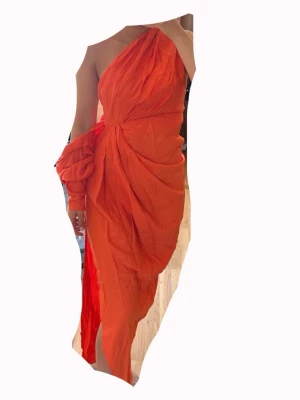 Orange oneshoulder långklänning - helt ny - Snygg orange långklänning med oneshoulder-design och draperade detaljer. Klänningen har en slits på sidan och ett coolt omlottliknande fall. Perfekt för dig som vill sticka ut med en unik och trendig look. Nypris: 1850kr. Fler bilder kan skickas på begäran.