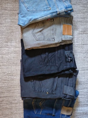 Fem par jeans i olika färger - Säljer fem par jeans i olika färger: ljusblå, grå, svart, mörkgrå och mörkblå. Klassisk femficksmodell med raka ben och detaljerade bakfickor. Materialet är denim och vissa har läderpatch bak i midjan. Perfekt för dig som vill variera din stil med olika tvättar. Skriv för frågor och priser. 