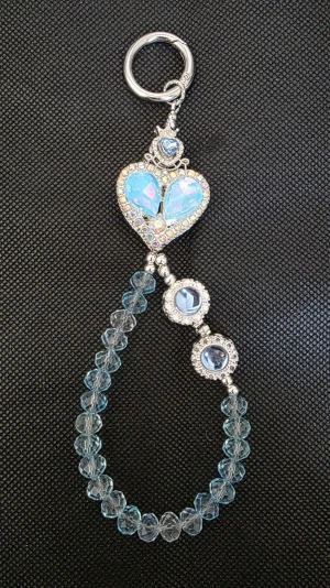  Superfin Y2K Bag Charm / Nyckelring i Ljusblå Kristall & Opal 💎 - Säljer denna otroligt fina och unika bag charm (eller nyckelring) som ger den perfekta Y2K-viben till din outfit! Perfekt för att piffa upp din favoritväska, jeansöglorna eller nyckelknippan. Mitten pryds av ett stort skiftande hjärta med opal-liknande lyster, omringat av glittrande strass. Den hängande öglan består av vackra fasetterade ljusblå pärlor och lyxiga detaljer med strassinfattade stenar.