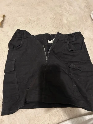 Jeanskjol - Svart jeanskjol från hm. Storlek: 158. Säljer då den sitter för tajt på mig. Skulle säga att den är mid-waist