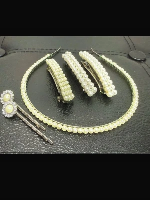Y2K Coquette Pärlset med Diadem, Hårklämmor och Blommiga Hårnålar – Romantisk Vintage Look - Romantiskt håraccessoarset med tydlig Y2K- och coquettekänsla. Innehåller pärldiadem, tre pärlklämmor och blommiga hårnålar. Diadem med ca 39 pärlor, klämmor ca 8 × 1 cm och blommor ca 1,7 cm. Basmetall med silvrig finish och imitationspärlor. Fint bruksskick med viss patina; en liten strass saknas. Perfekt till fest, bal eller vardag. Bundlerabatt vid köp av flera saker.  