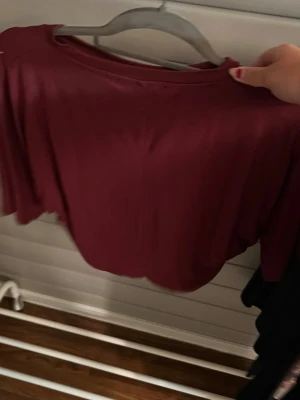 Vinröd långärmad topp - En enkel och stilren vinröd långärmad topp med rund hals. Toppen har en mjuk och följsam känsla, perfekt att matcha med jeans eller kjol. Passformen är normal och materialet känns lent mot huden.