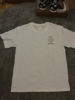 Vit Casa Blanca t-shirt med tryck - Säljer en vit t-shirt från Casa Blanca med stort tryck på ryggen och mindre tryck på bröstet. Klassisk passform och rund hals. Tillverkad i mjuk bomull, perfekt för en clean och stilren look.