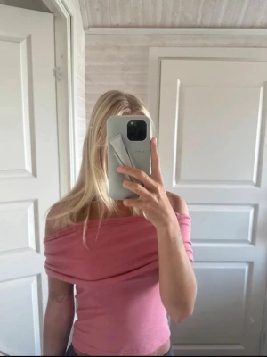 Rosa offshoulder topp från Motel - Trendig rosa offshoulder topp från Motel i mjukt ribbat material. Toppen är croppad och har en snygg, axelbandslös design som ger en cool vibe. Perfekt att styla med höga jeans eller kjol för en fräsch look.