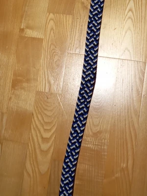 Blått flätat bälte med mönster - Snyggt flätat bälte i blått, svart och vitt med ett randigt mönster. Bältet har detaljer i brunt skinn vid spännet och metallspänne. Perfekt för att ge din outfit en cool touch.