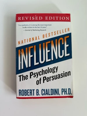 ”Influence: The Psychology of Persuasion” av Robert B. Cialdini - Boken "Influence: The Psychology of Persuasion" av Robert B. Cialdini, Ph.D. är en internationell bästsäljare om övertalningstekniker. Den utforskar sex grundläggande psykologiska principer som driver mänskligt beteende och beslutsfattande. Denna utgåva är en reviderad pocketutgåva. Ett par understrykningar och blyersanteckningar på några ställen, men i övrigt i mycket gott skick. Nypris 644:-. Bästa investeringen!  ISBN 978-0-06-124189-5.