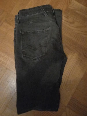 Svarta Replay jeans med raka ben - Snygga svarta jeans från Replay med klassisk femficksdesign och raka ben. Jeansen har diskreta slitningar och logga på fickan. Perfekta för dig som gillar en stilren look och vill ha ett par jeans som funkar till det mesta.