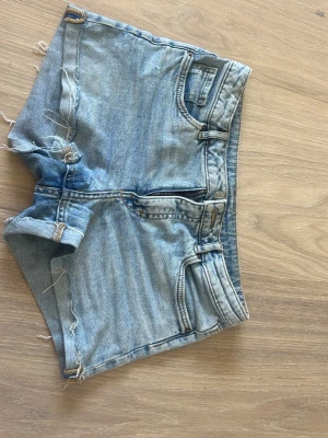 Ljusblå jeansshorts med fransar - Säljer ett par ljusblå jeansshorts i storlek 158. De har dragkedja och en knapp, lite fransar och även så man kan ha skärp.