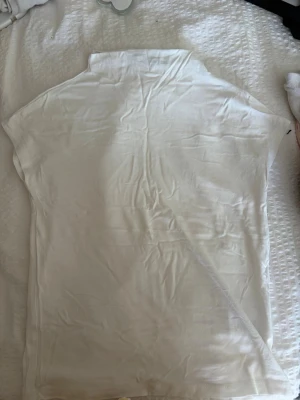 Vit kortärmad t-shirt med krage - En enkel och stilren vit t-shirt med korta ärmar och liten krage. Perfekt basplagg till garderoben, gjord i mjukt material som känns skönt mot huden. Passar till många olika stilar och tillfällen.