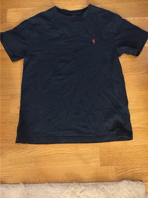 Mörkblå t-shirt från Polo Ralph Lauren - Jag säljer denna marinblå T-shirten från polo Ralph lauren som är köpt på kidsbrandstore i storlek M 175/96A💕 den är i fint skick och nypriset är 595kr💕 