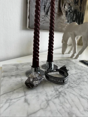 Svart och vit Christian Dior armband - Snyggt armband från Christian Dior i svart och vitt tyg med texten 'J'ADIOR' och 'CHRISTIAN DIOR'. Armbandet har dekorativa tofsar i ändarna och justerbar knytning. Perfekt accessoar för att lyfta din outfit med en exklusiv touch.