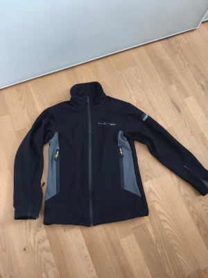 Svart vindjacka från Sail Racing - Snygg svart vindjacka från Sail Racing med Windstopper-material. Perfekt för blåsiga dagar. Passar dig som är 150 - 160cm lång . Pris kan diskuteras! 