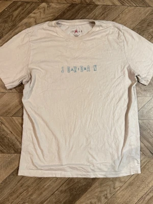 Vit Jordan t-shirt  - Säljer en vit t-shirt från Jordan med stilrent tryck på bröstet. Klassisk passform och rund halsringning. Perfekt för dig som gillar enkel och sportig stil.