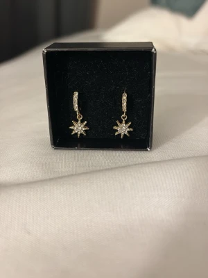 Guld öronhängen med sol - Säljer ett par guldiga öronhängen med solar/stjärnor med diamanter, använda en gång. Köpte på glitter för 150 o säljer för 89⭐️