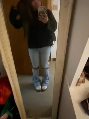 Ljusblå slitna jeans med hål - Säljer ett par ljusblå jeans med stora hål över knäna och raka ben. Jeansen har en avslappnad passform och är perfekta för en trendig streetstyle-look. Materialet ser ut att vara klassisk denim i bomull. Snygga att matcha med sneakers eller boots.