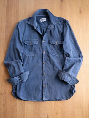 Blue Overshirt, size M - Säljer en blå overshirt med knappar framtill och två bröstfickor med lock. Skjortan har klassisk krage och är tillverkad i ett mjukt bomullstyg. Perfekt för en avslappnad och stilren look.