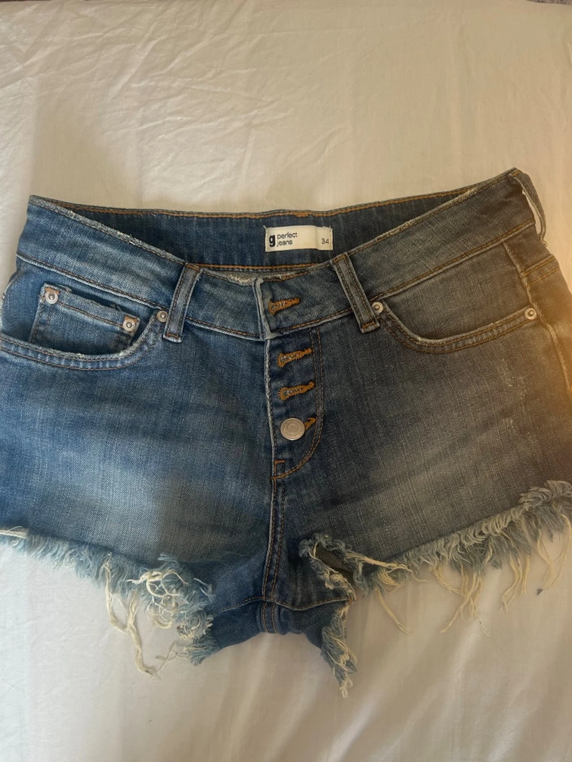 Lågmidjade blå jeansshorts med fransig kant