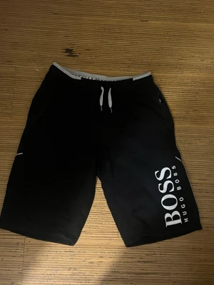 Svarta shorts från Hugo Boss storlek S  - Svarta shorts från Hugo Boss med vit logga längs ena benet. 150 kr för dem skickar paketet inom 24h 