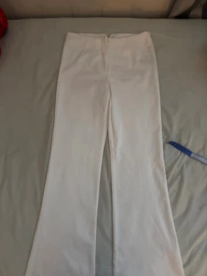 Vita byxor  - Säljer ett par vita leggings med utsvängda ben och hög midja. De är stretchiga och sitter tight upptill men blir vidare nedtill för en snygg siluett. Perfekta för dig som gillar en clean och enkel stil.