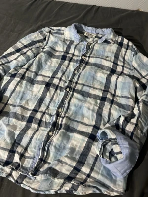 Rutig skjorta från Hampton Republic - Säljer en snygg rutig skjorta från Hampton Republic i blått och vitt. Skjortan har knappar framtill, klassisk krage och långa ärmar. Tillverkad i bomull och har en slim fit passform. Perfekt för dig som gillar en stilren och avslappnad look.