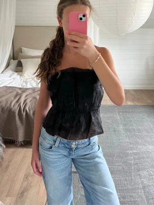 Svart tubtopp - Säljer en svart tubtopp från Bikbok i storlek xs. Toppen är axelbandslös och har en lätt utsvängd passform som ger en snygg siluett. Perfekt att styla med jeans eller kjol för en trendig look.