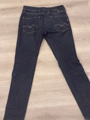 Replay Anbass Hyperflex - Säljer ett par mörkblå jeans med raka ben och klassiska kontrastsömmar. Jeansen har fem fickor och en enkel, stilren look som passar till det mesta. Materialet är kraftig denim som känns slitstark och bekväm.