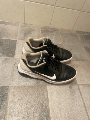 Golfskof från Nike  - Snygga svarta Nike sneakers. Skorna har gått sönder lite i hälen som ni kan se på ena bilden annars är dem i bra skick. Greppet under har slitits ut litegrann men ger inte stor påverkan 