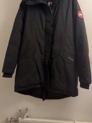 Ny dunjacka med päls - dam  - Snygg svart dunjacka med äkta päls. Logo canada goose. Ej o-r-g-i-n-a-l. Men jättefin kvalité och har QR koder och allt! Ny med prislapp. Det står storlek xxxl men den är liten i storlek och uppskattar den som en Large. Finns så man kan spänna till jackan så den blir mindre inuti. Jackan är något längre baktill och finns en dragkedja bak som man kan öppna. 