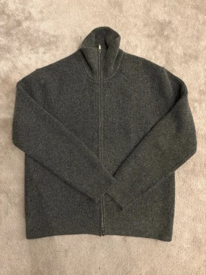 Grå stickad ziptröja från H&M - Mysig grå stickad tröja från H&M med dragkedja framtill och hög krage. Regular fit. Aldrig använd 
