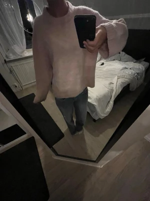 Ljusrosa oversized stickad tröja - Mysig ljusrosa stickad tröja med oversized passform och rund hals. Tröjan har långa ärmar och ribbade muddar vid ärmslut och nederkant. Perfekt för kalla dagar och enkel att styla med jeans eller kjol.