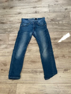 Blå slim fit jeans med stretch - Snygga blå slim fit jeans med stretch och klassisk femficksmodell. Jeansen har slitningar och ljusare partier på låren för en trendig look. Tillverkade i denim med super stretch för extra komfort. Perfekta för dig som gillar en avslappnad men stilren stil . Storlek 150