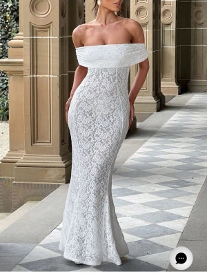 Vit offshoulder spetsklänning - Elegant långklänning i vit spets med offshoulder-ringning och figurnära passform. Klänningen har en insydd underkjol!