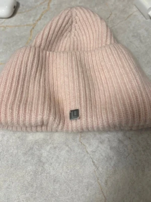Rosa Lasessor Beanie - RRP €50. A soft, fully fashioned ribbed beanie. The fold-up cuff provides extra warmth for the forehead and ears. 10% angora, 34% viscose, 38% nylon, 18% polyester.