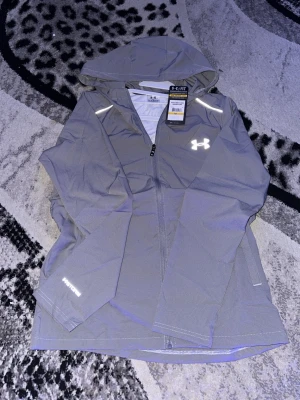 Under armour vindjacka  - Grå aldrig använd under armour vindjacka, jackan är i storlek M men jag skulle nog säga att den passar både S och M.