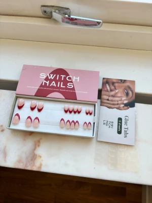 Switch Nails press-on naglar röd fransk - Snygga press-on naglar från Switch Nails i en modern röd fransk design. Naglarna är mandelformade och har en nude bas med röd kant. Setet innehåller flera storlekar och 2 glue tabs för enkel applicering. Perfekt för dig som vill ha trendiga naglar snabbt.