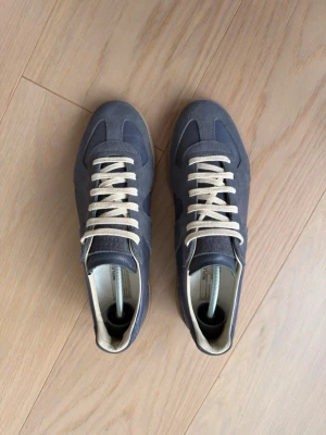 Blå sneakers med beige sula - Snygga sneakers i blått läder och mocka med beigea skosnören och klassisk gummisula. Skorna har en låg silhuett och stilrena detaljer som passar till många olika outfits. Perfekt för dig som gillar en clean och tidlös look. ( storlek 43, 28cm inner )