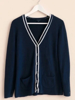 Marinblå kofta Tommy Hilfiger Preppy y2k - Stilren marinblå kofta med vita kanter och knappar från Tommy Hilfiger. V-ringad modell med två fickor framtill och lång ärm. Perfekt till lager på lager och enkel att matcha med olika outfits.
