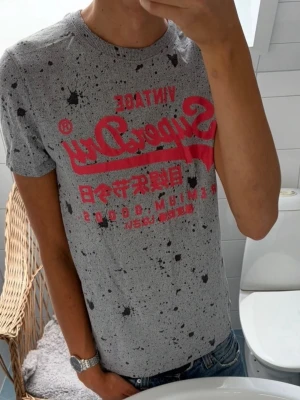 Superdry *Paintsplatter* T-Shirt ~ Vintage - Unik Vintage Superdry Paintsplatter T-Shirt | Storlek: S | Passform: Normal Fit | Sällsynt och unik modell | Färg: Grå/Rosa, Tryck | Skick: 9/10 Inga defekter | Pris ej hugget i sten! 🏄‍♂️☀️