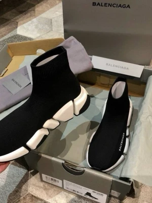 Balenciaga Speed Trainer svarta sneakers - Ikoniska Balenciaga Speed Trainer sneakers i svart med vit chunky sula. Stickad strumpdesign som sitter tight runt foten och BALENCIAGA-logga på sidan. Superlätta och flexibla, perfekta för en trendig streetwear-look.
