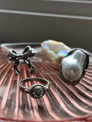 Ringar - Tre ringar, använda men i bra skick. Ring med pärla och ring med rosett är justerbara. Köpta antingen secondhand eller på loppis. Köp alla 3 för 20kr eller 8kr st.