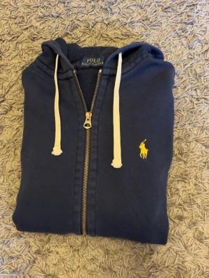 Ralph lauren hoodie - Tjena! Säljer en blå Ralph lauren zip hoodie i lite vintage stil. Den är i bra skick men har ett litet hål på armen (sista bilden). Det är dock väldigt litet och är ingenting som syns när man har den på sig. Skriv gärna vid frågor eller intresse! Pris kan diskuteras!:)