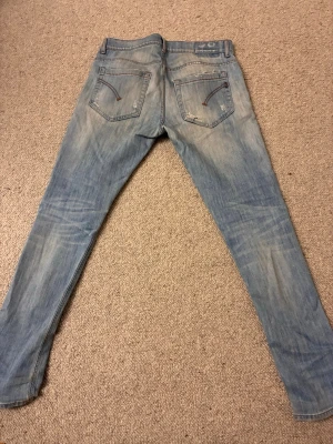Vintage Dondup George jeans - Säljer ett par ljusblå Dondup George slim fit jeans med riktigt snygga slitningar och tvättade detaljer. Skicket på Jeansen är 9/10 vilket gör det ännu svårare att behöva sälja dom vidare! Perfekta för en avslappnad och trendig stil.