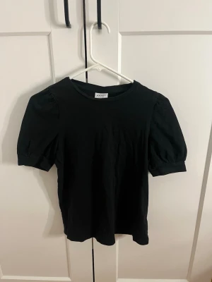 Svart puffärmad topp från Aware - Snygg svart topp från Aware med puffärmar och rund halsringning i storlek xs