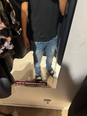 Jeans med slitningar  - Säljer ett par ljusblå jeans med  och slitningar på benen. Jeansen har hål vid knäna och klassisk femficksdesign. Perfekta för dig som gillar en avslappnad och trendig stil.