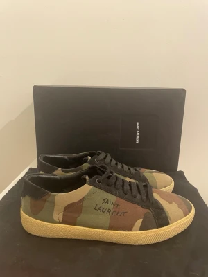 Camoflauge Saint Laurent skor  - Saint Laurent court classic väldigt eftertraktad| Camoflauge färgade|Stolrek 41 passar 42| 8/10 skick, en liten defekt bak i väster skor men som varken syns eller känns också lite limmad vid sulan  |Orginal box, dustbag, kuvert med information och äktehets kort medkommer| priset är ej fast!, hör av dig vid funderingar! Obs, tillverkas ej längre, nypris 7000kr!
