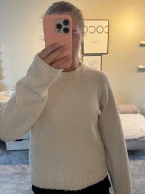 Vit fluffig stickad tröja - Mysig ljusrosa stickad tröja med rund hals och långa ärmar. Tröjan har en fluffig struktur och ribbstickade muddar vid ärmslut och nederkant.💓