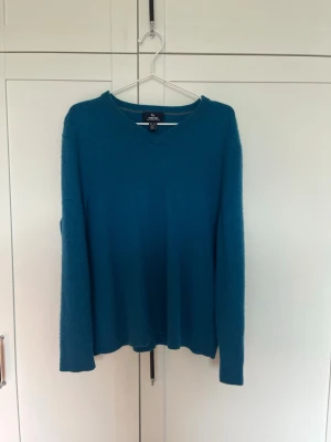 Blå cashmere tröja  - Mysig blå vintage stickad tröja i 100% cashmere. Tröjan har v-ringning, långa ärmar och ribbade muddar. Perfekt för dig som vill ha något både stilrent och bekvämt i garderoben. Har en liten mer avslappnad passform som kan liknas vid en klassisk Acne Studios tröja. Tröjan har minskat i tvätten så sitter som en S.